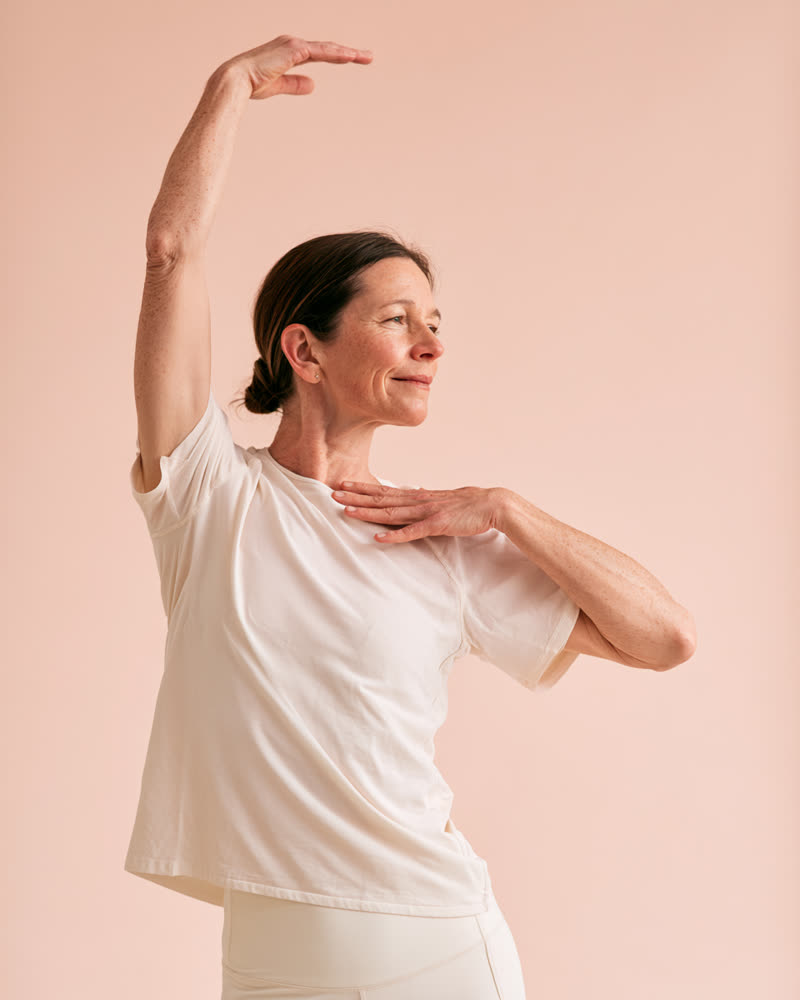 Woman reaching up with a hand on her shoulder — illustrative image
